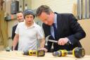 Prime Minister David Cameron visiting a New Enterprise Zone at Mobbs Way in Lowestoft. Steven Butcher showing the Prime Minister a large door he's working on and even letting him hammer in a wooden dowel.   Picture: James Bass