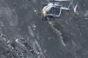 A recue helicopter flies over debris of the Germanwings passenger jet, scattered on the mountain side, near Seyne les Alpes, French Alps, Tuesday, March 24, 2015. A Germanwings passenger jet carrying at least 150 people crashed Tuesday in a snowy, remote 