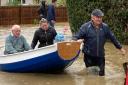 Simon O'Brien (right) using his homemade boat, which he built for his grandchildren, to rescue elderly residents from their home in the village of Debenham, Suffolk, where people were cut off by flood water during Storm Babet.