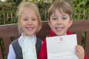 Olivia and George holding up the letter from King Charles and Queen Camilla