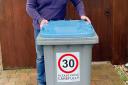 Suffolk county councillor Stuart Lawson, who represents Kesgrave and Rushmere St Andrew, with a wheelie bin bearing one of the stickers warning motorists about the speed limit.