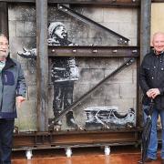 Art dealer John Brandler (left), with garage owner Ian Lewis, with Banksy's Season's Greetings prior to its removal to an art gallery.
