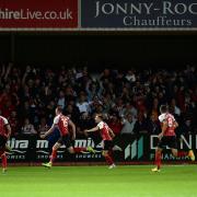 Home players celebrate after scoring the winning goal at Cheltenham Town.