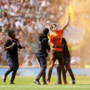 A Just Stop Oil protester is escorted off the pitch during the Premiership final at Twickenham