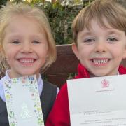Olivia and George holding up the letter from King Charles and Queen Camilla