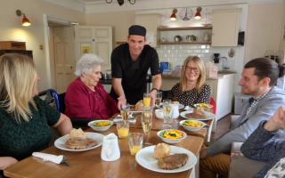 Paul Westall serves a special birthday meal to a resident of The New Deanery and her family.